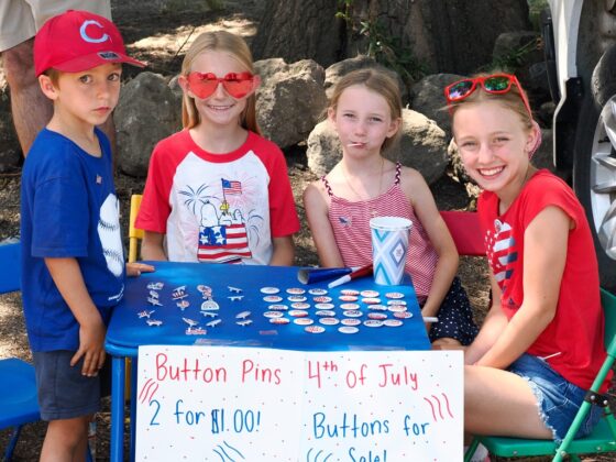 From left, a young vendor waits for customers while children display patriotic button pins for sale during the Grimes 175th Anniversary celebration on July 4. Photo by Chris Pedigo.