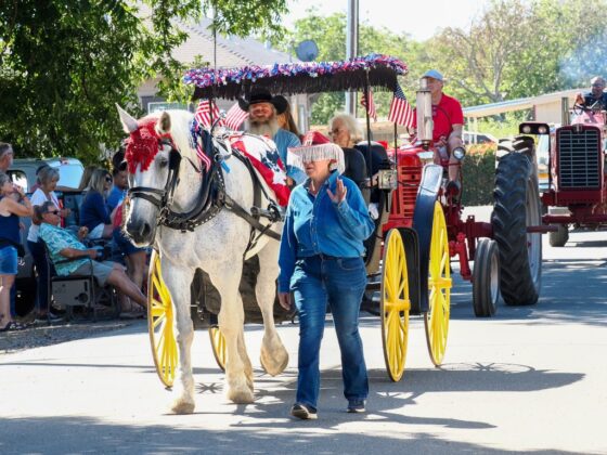A horse-drawn wagon decorated in patriotic colors rolls through the Grimes 175th Anniversary and Fourth of July parade, followed by vintage tractors on July 4. Photo by Chris Pedigo.